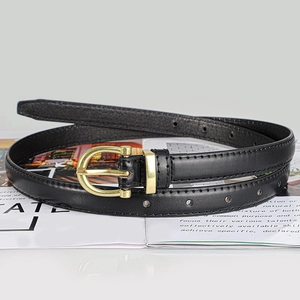 Detailed macro view of black slim leather belt with a classic gold pin buckle on magazines