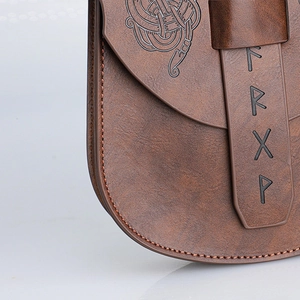 Vista dettagliata delle rune vichinghe e motivi celtici incisi sulla borsa in pelle vintage