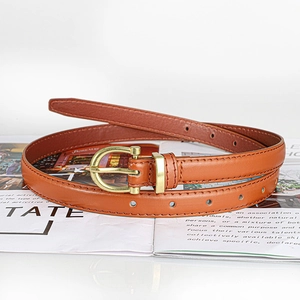 Close-up of amber brown leather belt with gold D-buckle on a magazine display