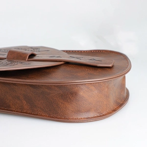 Dettaglio ravvicinato della borsa marrone in ecopelle con rune e motivi medievali a sbalzo