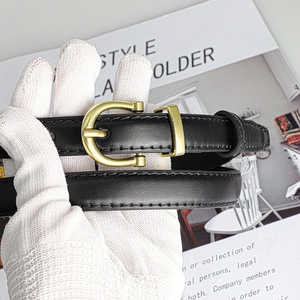 Close-up of classic black leather belt with gold horseshoe buckle and neat edge stitching