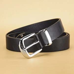 Détail d'une ceinture en cuir noir grainé avec boucle argentée polie sur fond beige