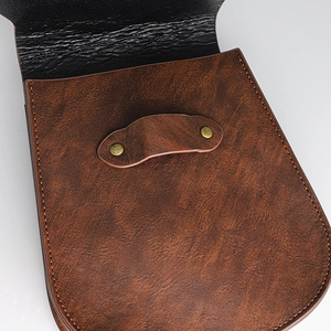 Dettaglio ravvicinato di borsa vintage in pelle marrone con rivetti in bronzo e cuciture