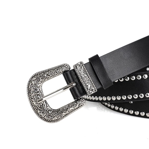 Detail of western style belt featuring vintage floral engraved silver buckle and rivets