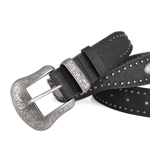 Détail de la ceinture vintage noire avec boucle gravée florale et rivets métalliques