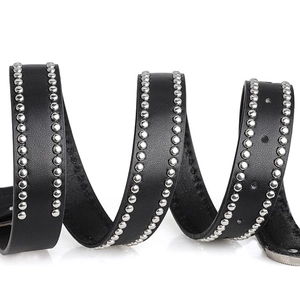 Macro view of black punk leather belt featuring silver round rivets and metal tip