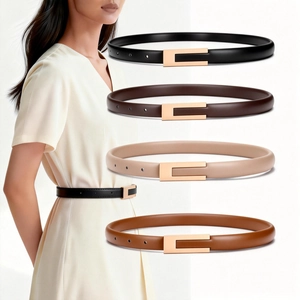 Detail of four thin leather belts in black and brown with golden U-shaped buckles