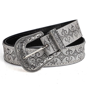 Detail of western cowboy belt featuring engraved buckle and silver studded leather