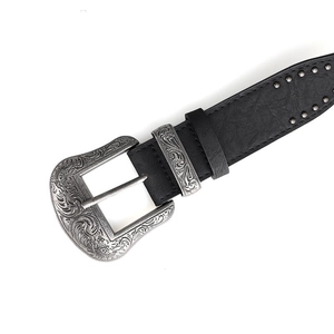 Détail de la boucle gravée vintage et des rivets métalliques sur ceinture noire