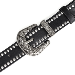 Detail of western punk black leather belt featuring silver studs and engraved floral buckle