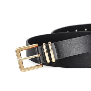 Detail van een zwarte leren riem met gepolijste gouden gesp en dubbele metalen lussen