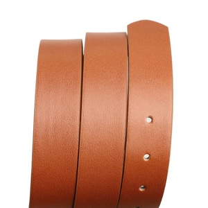 Détail de la ceinture en cuir marron montrant la texture grainée et les œillets ronds