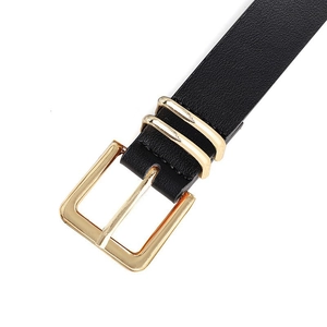 Detail van een dunne zwarte leren riem met klassieke gouden metalen gesp en twee lussen