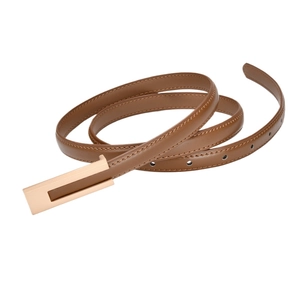 Detailed macro view of the slim brown leather belt with polished gold rectangular buckle