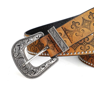 Detail of western cowboy belt featuring vintage floral carved buckle and rivet studs