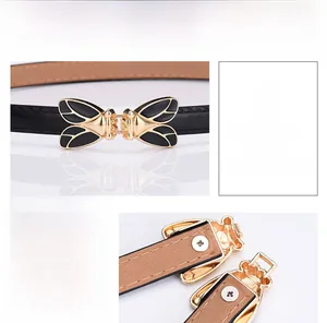 Detailed close-up of golden bee buckle and black faux leather texture on slim waist belt