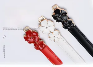 Detail of red, white, and black skinny belts with dual floral enamel buckles and gold accents