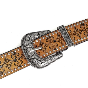 Detailed macro of vintage western belt featuring floral carvings and silver metal rivets