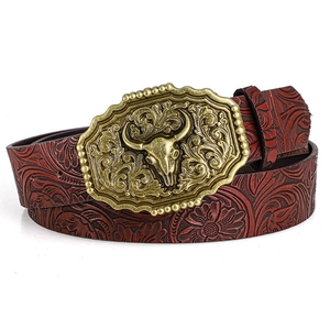 Detail of western bull skull buckle and embossed floral patterns on brown leather belt
