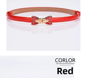 Detail of red thin waist belt featuring a gold bow buckle with red enamel drip finish