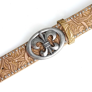 Détail d'une ceinture en cuir embossé avec clous et boucle fleur de lys vintage