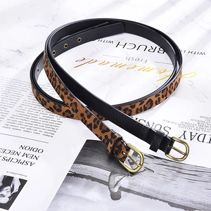 Detail of slim leopard print and black waist belts with bronze metal pin buckles