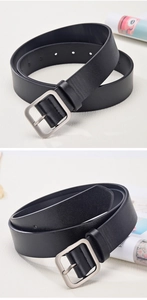 Detail of vintage black leather belt with matte silver square buckle on white fabric