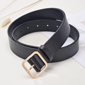Women's black leather belt with square gold buckle and magazine prop on tabletop