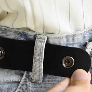 Close-up of black elastic invisible belt with silver metal buckle on denim jeans
