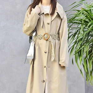 Boheemse beige macramé riem met ronde houten gesp gedragen op een klassieke trenchcoat