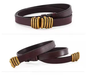 Detail view of burgundy leather belt with retro gold cylindrical metal buckle