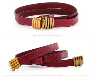 Detail of slim dark red leather belt with a textured vintage gold metal buckle