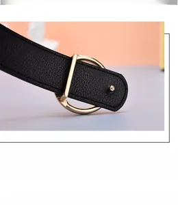 Détail de la ceinture en cuir grainé noir avec une boucle dorée en forme de D