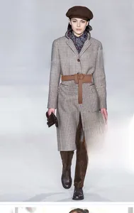 Detail of a brown leather knot belt styled on a plaid coat for an elegant autumn look