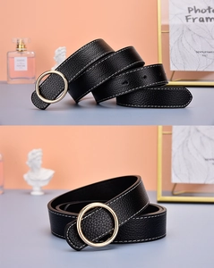 Détail de la ceinture en cuir noir avec boucle dorée ronde et coutures contrastées
