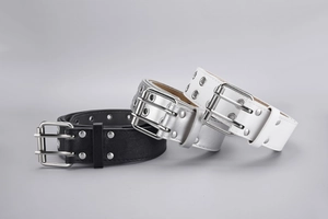 Detail of three punk style belts in black, silver and white with double metal eyelets