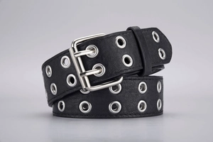 Detail of black punk belt featuring double-prong silver buckle and metal eyelets texture