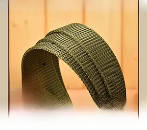 Detail of dark green woven canvas belt with pin buckle holes on wooden background