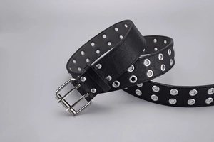 Close-up of black punk belt featuring double row silver eyelets and metal double pin buckle