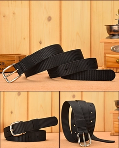 Detail view of black woven canvas belt with silver pin buckle on rustic wood background