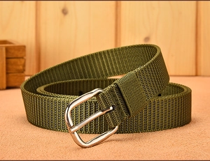 Detailed view of military green canvas belt with silver pin buckle on a wooden table
