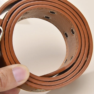 Detail eines braunen Ledergürtels mit doppelten Metallösen und präzisen Steppnähten