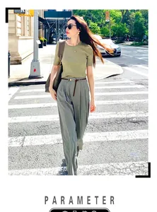 Street style shot of a woman in green knit top and grey pants with a slim brown belt
