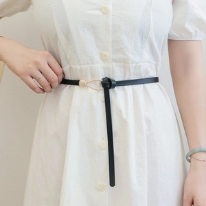 Women black slim leather belt with gold irregular buckle on white dress for waist cinching