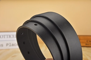 Close-up of black textured leather belt with precise punch holes on a wooden background