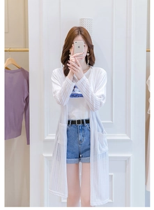 Détails d'un cardigan blanc en maille ajourée avec rayures verticales et grandes poches