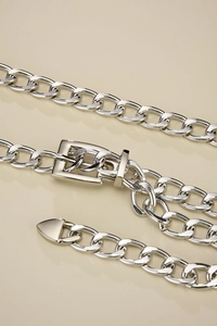 Detailed close-up of a shiny silver metal curb chain belt with a polished square pin buckle