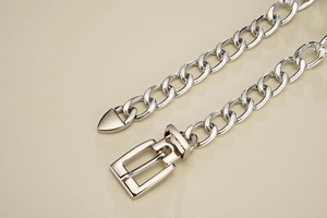 Macro shot of silver Cuban link chain belt featuring square pin buckle and high-polish finish