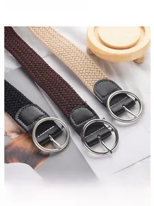 Détail de ceintures tressées extensibles en noir, marron et beige avec boucles argentées
