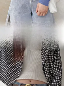 Détail d'une fine ceinture en cuir marron portée avec un blazer pied-de-poule et jean